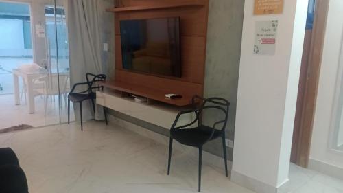 a living room with three chairs and a tv at Casa com piscina e hidromassagem praia Enseada. in Guarujá