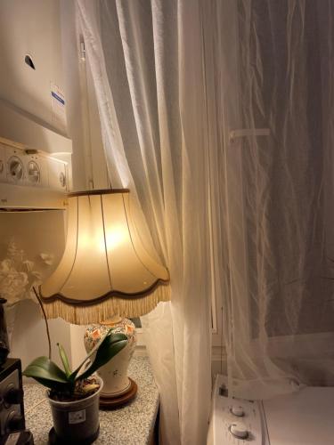 une lampe assise sur une table à côté d'un rideau dans l'établissement Appartement Paris, à Paris