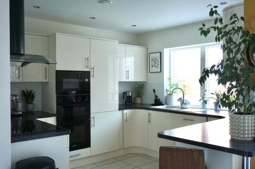 a kitchen with white cabinets and a sink and a window at Manor Park View in Norwich