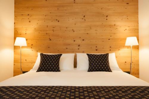 a bedroom with a white bed with two lamps at Chalet Alfonz in Bormio