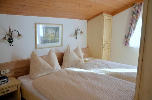 a bedroom with a bed with white sheets and pillows at Haus Sonnleiten in Gerlos