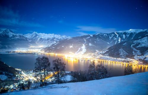 a view of a city in the snow at night at Pension Alpentraum in Zell am See