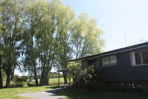 a black house with trees in the background at Willow's End in Hamurana