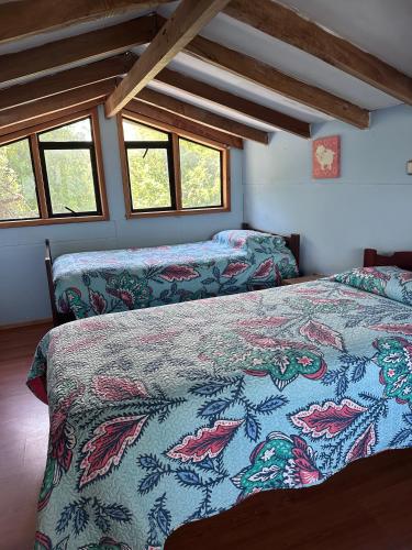 una camera da letto con due letti in una stanza con finestre di Cabañas Paihuén a Pucón