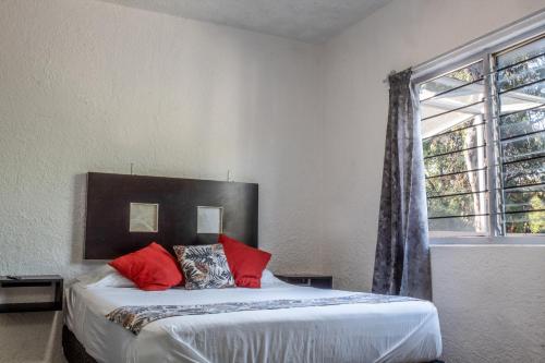 a bedroom with a bed with red pillows and a window at Céntrico Estudio en Chapalita Tu Refugio Ideal 15 in Guadalajara