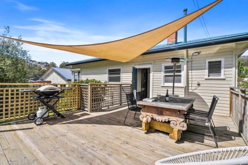 a grill on a wooden deck with a house at Cascade Cottage adjoining World Heritage Site in Hobart