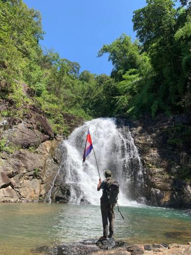 a man holding a flag in front of a waterfall at Banlung Mountain View Treks & Tours in Banlung