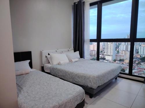 two beds in a room with a large window at View of the whole Georgetown in George Town