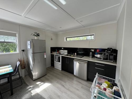 a kitchen with a stainless steel refrigerator and a table at The Hidden Cottage in Papamoa