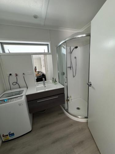 a bathroom with a shower and a sink and a mirror at The Hidden Cottage in Papamoa