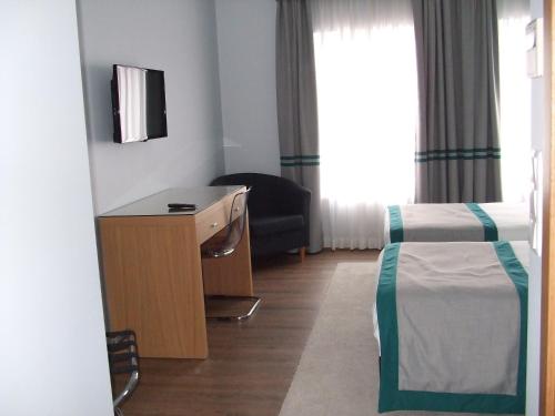 a hotel room with a bedroom with a bed and a desk at Alojamento do Zezere in Ferreira do Zêzere