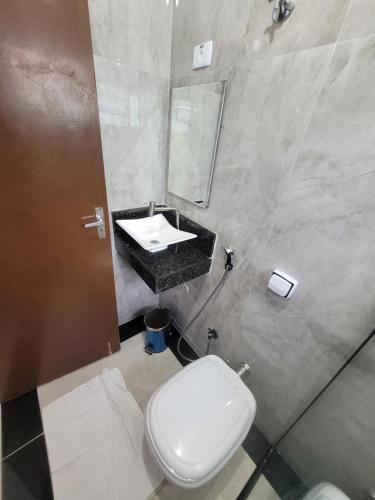 a bathroom with a white toilet and a sink at Hospedaria São Benedito in Guararema
