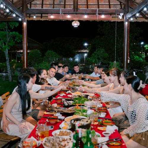 a group of people sitting at a long table with food at Mộc Villas in Phuoc Buu