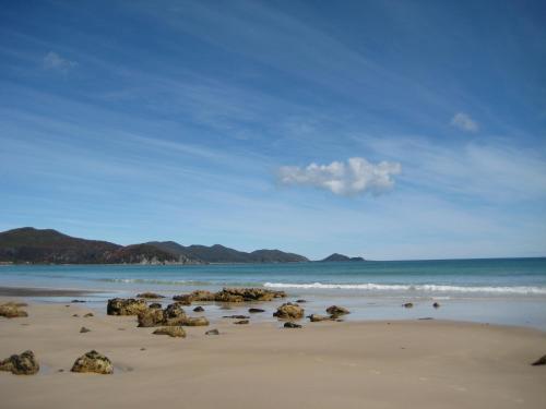 a beach with rocks in the sand and the ocean at Sisters Beach House in Sisters Beach