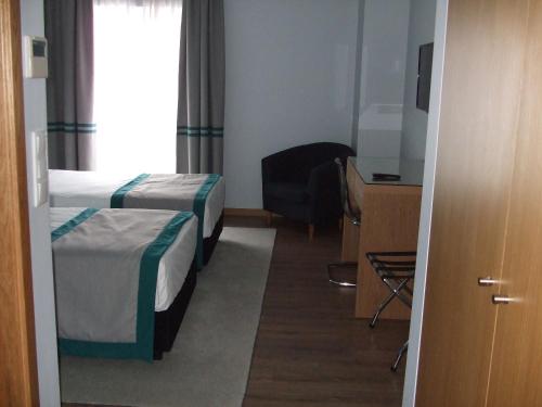 a hotel room with two beds and a chair at Alojamento do Zezere in Ferreira do Zêzere