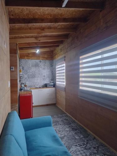 a living room with a blue couch and a kitchen at Departamento un Ambiente in Frutillar