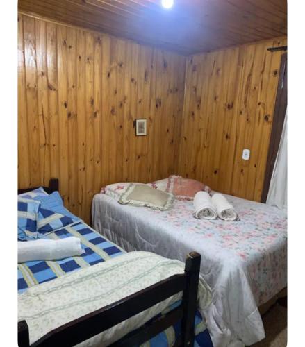 two beds in a room with wooden walls at Casa de madeira 262 in Campos do Jordão