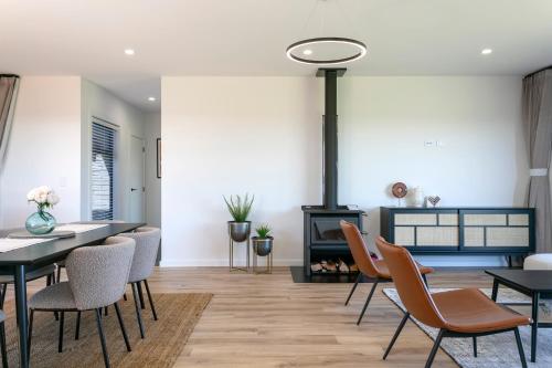a dining room with a table and chairs and a fireplace at Taupo New Retreat - Stylish, Convenient and Gully track to the lake in Taupo