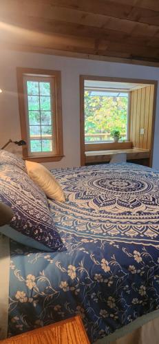 a bed in a bedroom with two windows at Hummingbird B&B in Gabriola