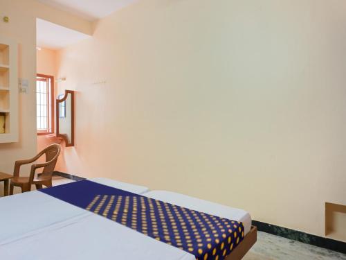 a bedroom with a bed and a table and a chair at Hotel O Vel Vel Guest House in Palani