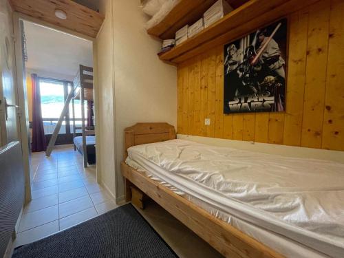- une chambre avec un lit et un mur en bois dans l'établissement Studio familial au centre du village avec balcon et casier à ski - FR-1-624-163, à Samoëns