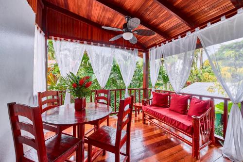 a porch with a table and chairs and a couch at Hotel El Encanto in Cahuita