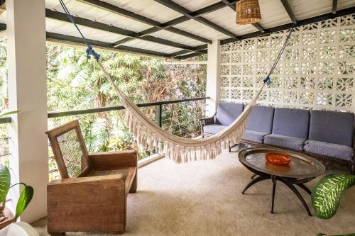 a porch with a hammock and a table and chairs at TUKI Nest Spacious Home with Garden View & Self-Service Breakfast - Large Porch, Subic Monkeys, Pet Friendly with a Fee in Santa Rita