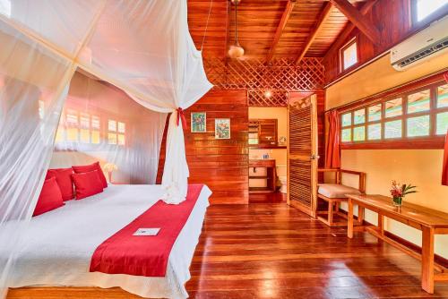 a bedroom with a bed with a mosquito net at Hotel El Encanto in Cahuita