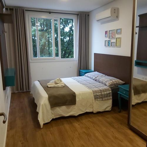 a hotel room with a bed and a window at Apartamento aconchego in Gramado