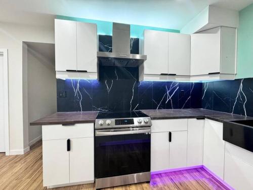 a kitchen with white cabinets and a stove at Charming & Compact Retreat in St. Albert
