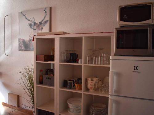 Elle comprend une armoire blanche avec un four micro-ondes et un réfrigérateur. dans l'établissement Charmant triplex ensoleillé à Font-Romeu - FR-1-580-122, à Font-Romeu-Odeillo-Via