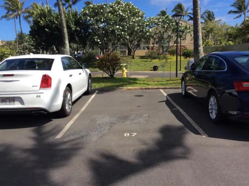 a white car and a black car parked in a parking lot at Couple's Retreat - Get Away to Turtle Bay in Kahuku