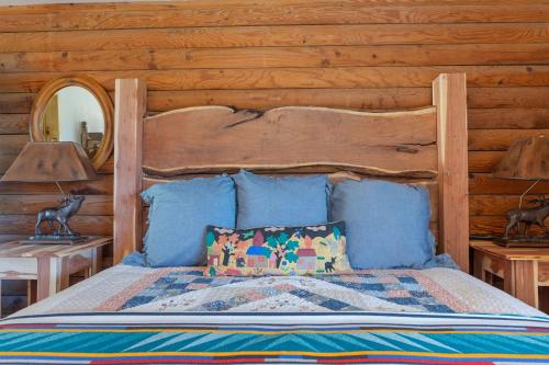 a bedroom with a bed with a wooden wall at Guadalupe Bluff Log Cabin in Kerrville