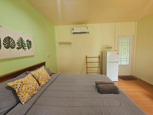 a bedroom with a large bed and a refrigerator at Baan suan khun ta บ้านพักสวนคุณตา in Ko Chang