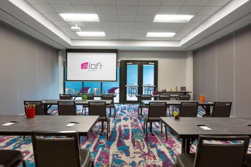 a conference room with tables and chairs and a projection screen at Aloft San Juan in San Juan