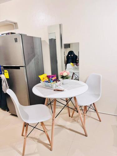 a white table with two chairs and a refrigerator at Asahel Cozy Crib Budget studio with Netflix in Buri