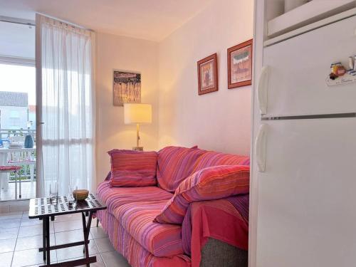- un salon avec un canapé rouge et un réfrigérateur dans l'établissement Appartement 6 couchages à 100m plage avec terrasse, parking, lave-linge et piste cyclable proche - FR-1-251-550, au Lavandou