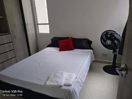 a bedroom with a bed with two towels and a fan at El Indi0 Acostado in Villavicencio