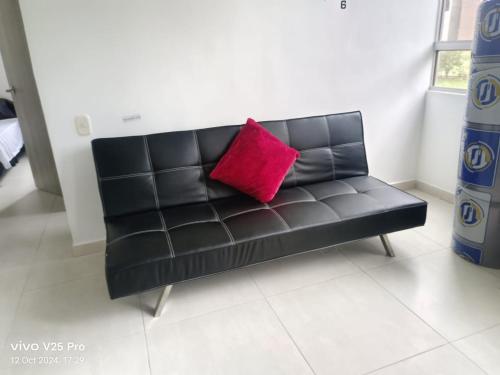 a black leather couch with a pink pillow on it at El Indi0 Acostado in Villavicencio