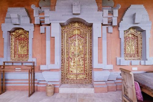 a large gold door in a building with stacks of towels at Gayatri in Ubud