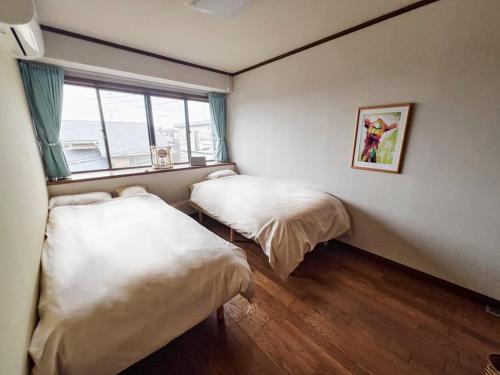 a bedroom with two beds and a window in it at Kamakura House in Kamakura