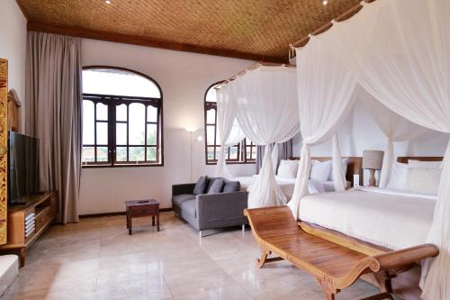 a bedroom with a canopy bed and a couch at Gayatri in Ubud