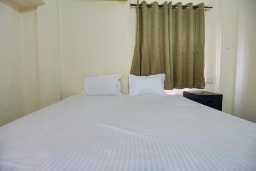 a large white bed with two pillows in a bedroom at Hotel O Elite Inn in Nagpur