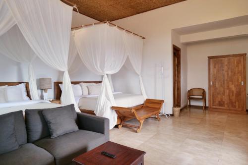 a bedroom with a couch and a bed with curtains at Gayatri in Ubud
