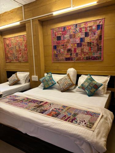 a bedroom with two beds and a quilt on the wall at Hotel Fotiya jaisalmer in Jaisalmer
