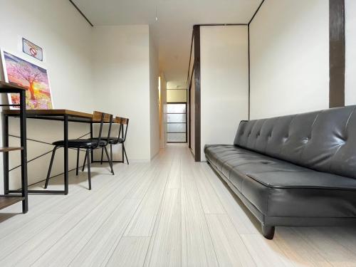 a living room with a leather couch and a table at A&C House 新大阪 in Osaka
