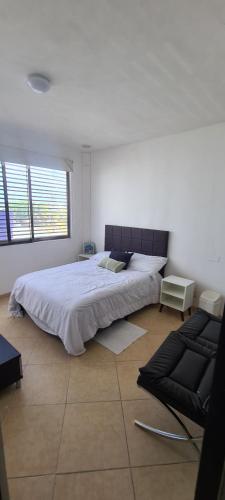 a bedroom with a large bed and a chair at Kaan Town Houses Cancún in Cancún