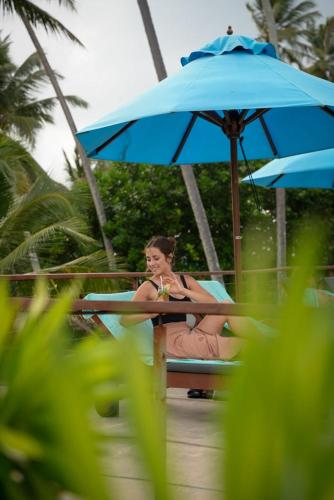 a woman sitting at a table under an umbrella at R Degrees Boutique Hotel & Spa in Ambalangoda