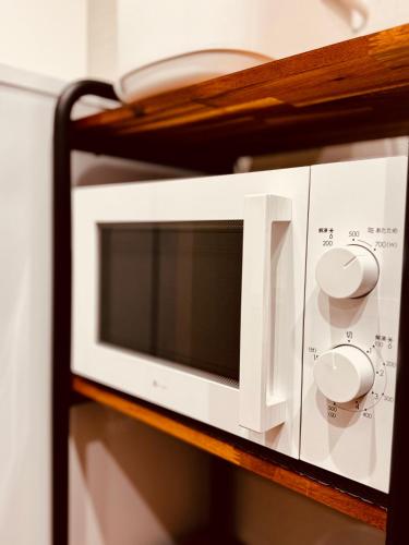 a white microwave oven on a wooden shelf at Niseko Purr 101 in Kutchan