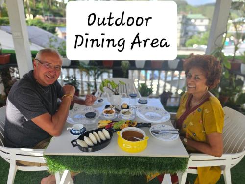 a man and a woman sitting at a table with food at S & B Dreams House in Munnar